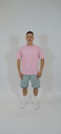 Person wearing a pink t-shirt and denim shorts on a white background