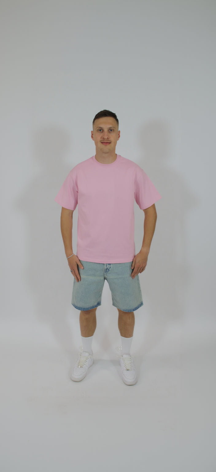Person wearing a pink t-shirt and denim shorts on a white background