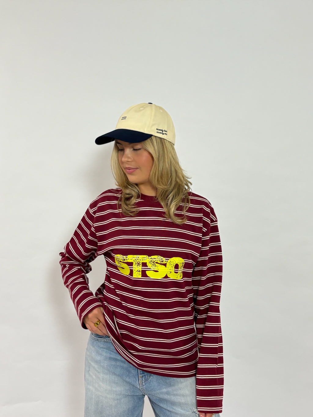 Cap crème met navy klep van 72.71 Clothing – gedragen door een vrouwelijk model met een gestreepte longsleeve