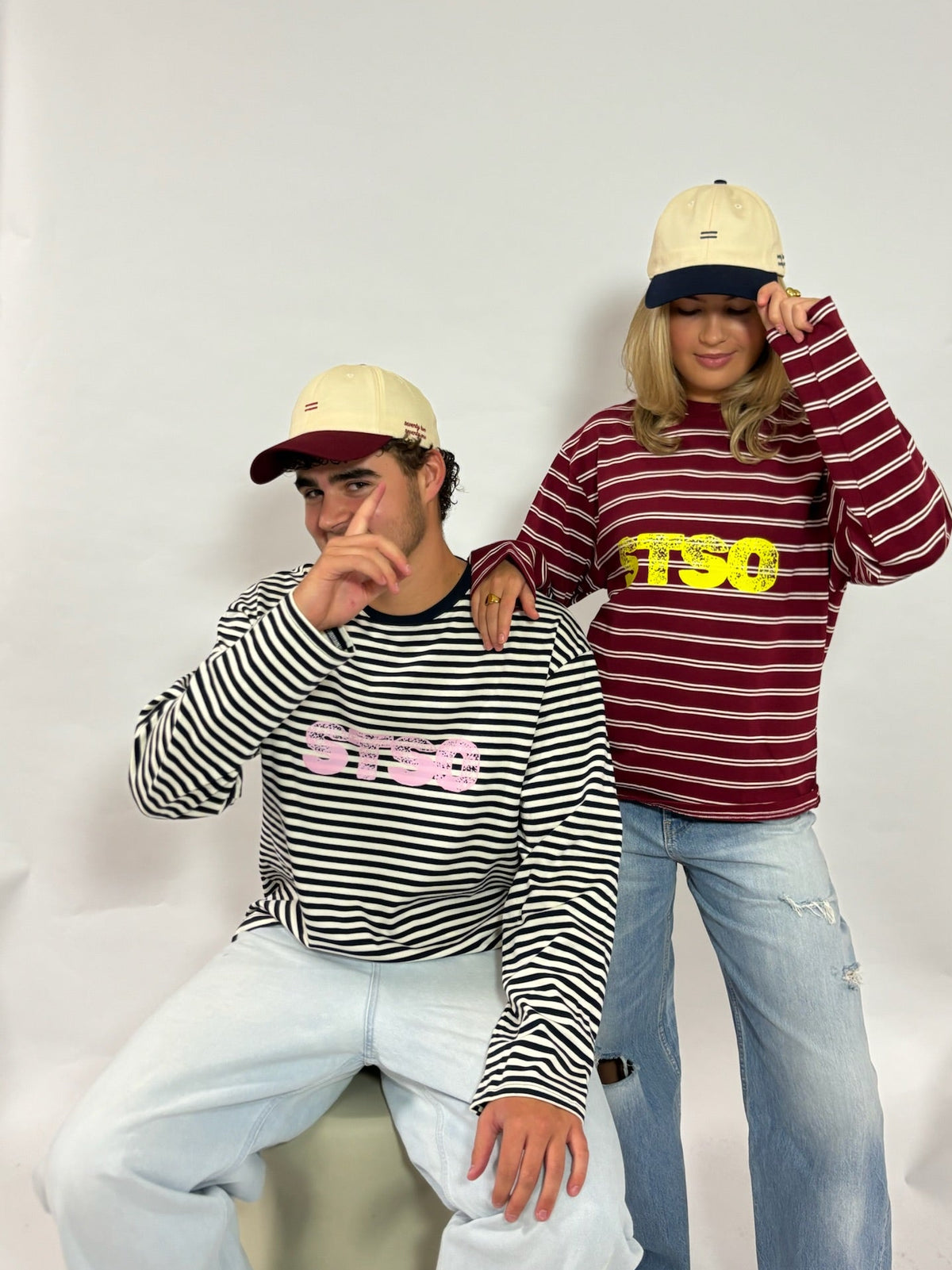 Cap crème met navy klep van 72.71 Clothing – gedragen door twee modellen met gestreepte longsleeves