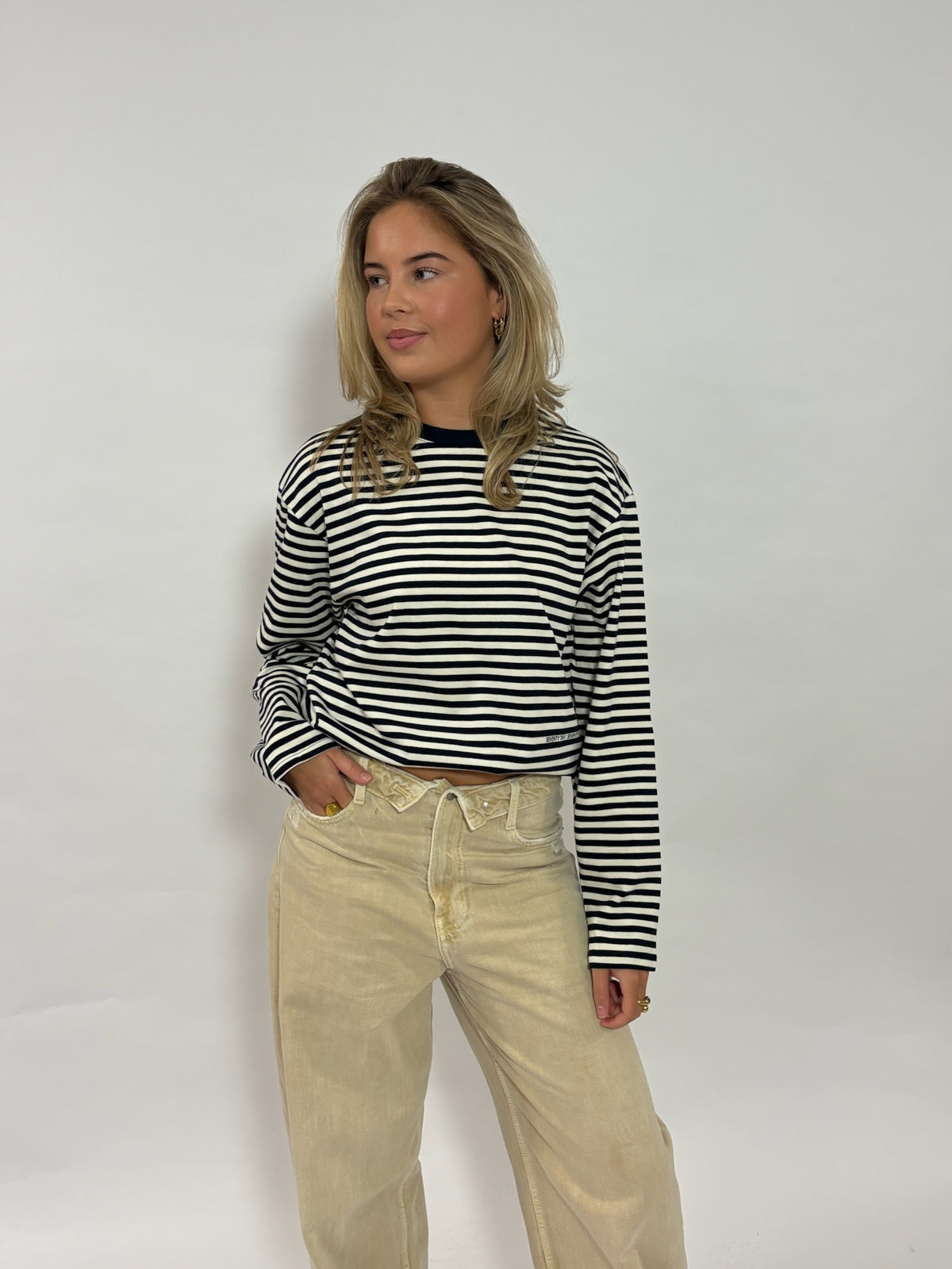 Gestreepte longsleeve navy – Seventy Two Seventy One van 72.71 Clothing – voorkant, gedragen door een vrouwelijk model met een beige ribbroek