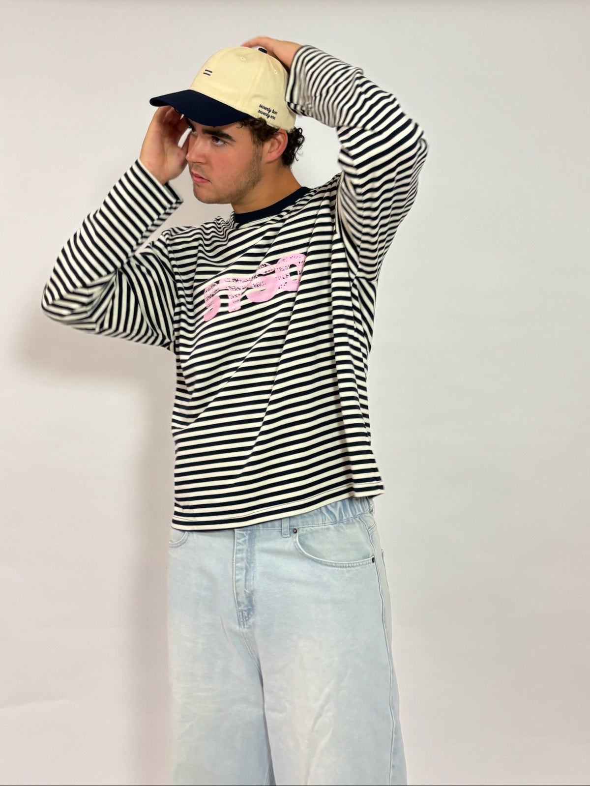 Cap crème met navy klep van 72.71 Clothing – gedragen door een mannelijk model met een gestreepte longsleeve